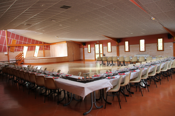 Salle avec tables, chaises, nappes, verres, couverts.