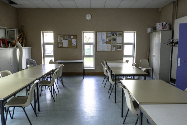 Salle avec tables, chaises, tableaux, armoires et horloge.