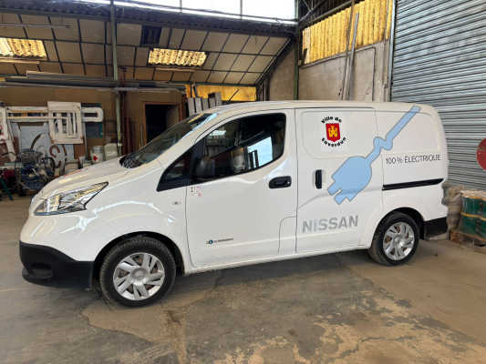 Utilitaire Nissan blanc dans un garage avec outils et étagères.