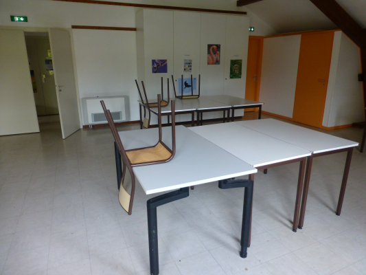 Salle avec tables, chaises, étagères et posters.