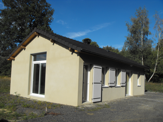 Bâtiment jaune avec toit noir, fenêtres et portes.