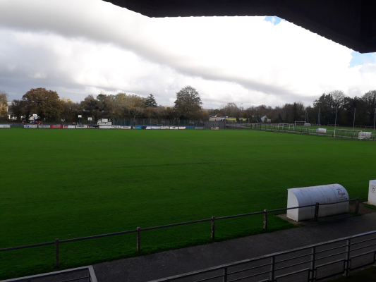 Terrain de sport avec tribunes, clôtures et abri.