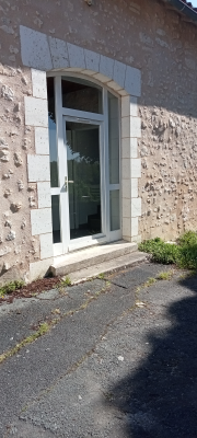 Porte en verre avec cadre de pierre, allée de béton.