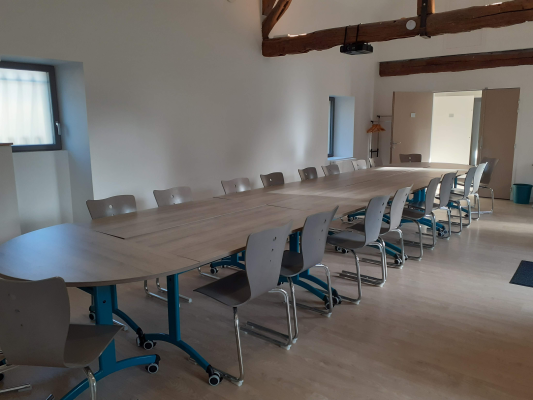 Salle de réunion avec table, chaises et porte-manteau.
