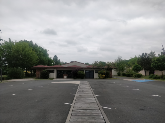 Parking avec allée en bois, bâtiments et arbres.