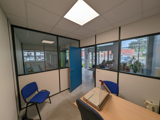 Bureau avec table, chaises, boîte en carton, porte et fenêtres.