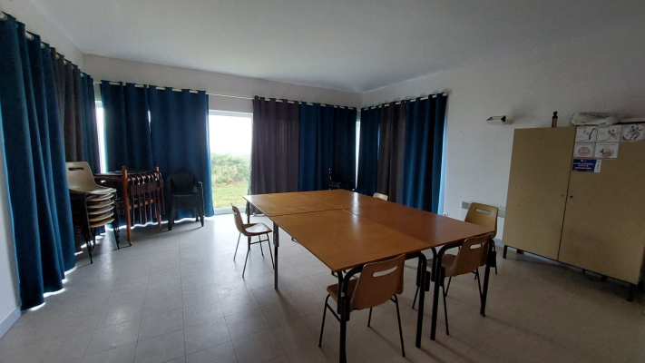 Salle avec table, chaises, armoire et fenêtres avec rideaux.