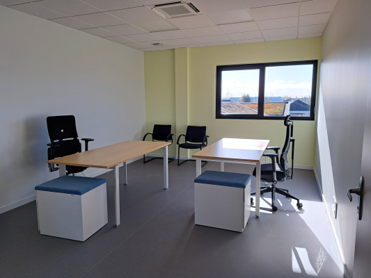 "Bureau équipé de tables, chaises, ottomans et fenêtre."