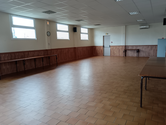 Salle avec bancs en bois, tables, carrelage et fenêtres.