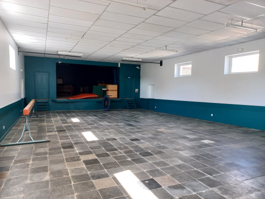 Salle avec sol carrelé, mur bleu vert, appareil de musculation, miroir et porte.