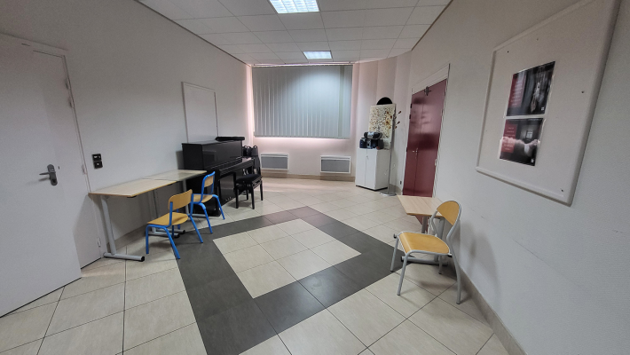 Salle avec piano, tables, chaises, armoire.