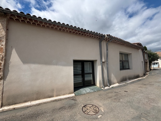 Maison avec toiture de tuiles, porte et fenêtre. Rue pavée avec regard.