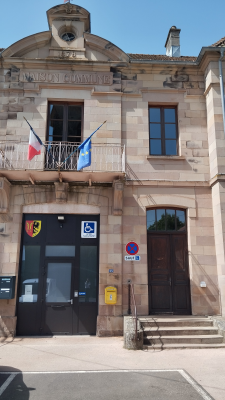 Bâtiment avec entrée, fenêtres, drapeaux, et panneaux de signalisation.