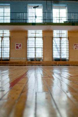Salle de sport avec parquet, fenêtres et panneaux.
