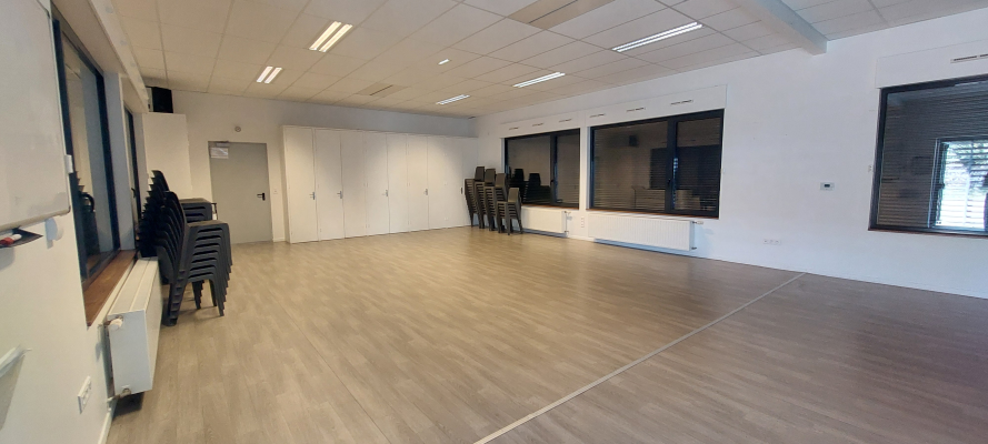 Salle vide avec chaises, portes, fenêtres et radiateurs.