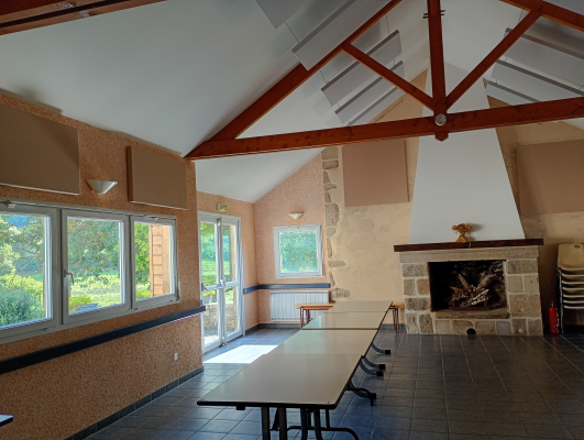 Pièce avec tables, chaises, cheminée, fenêtres, poubelle.