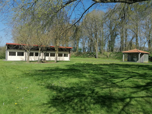 Deux bâtiments avec toits rouges, table de pique-nique, gazebo, pelouse verte, arbres.