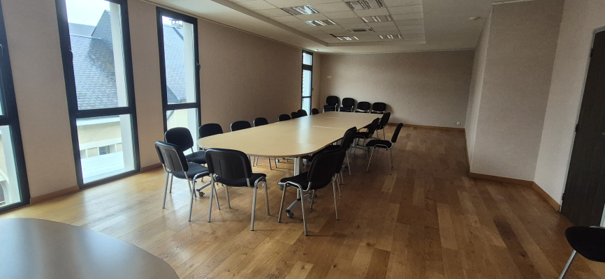 Salle de réunion avec table, chaises et fenêtres.
