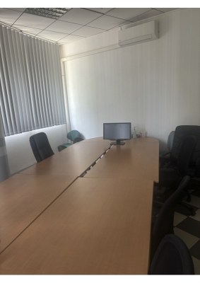 Salle de réunion avec table, chaises, ordinateur et climatiseur.