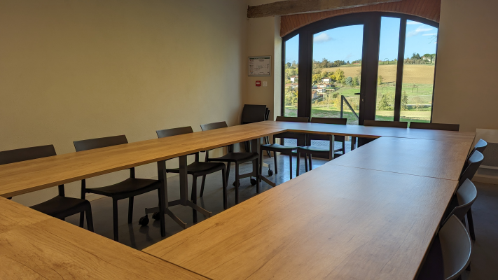 Salle de réunion avec table, chaises et fenêtres.