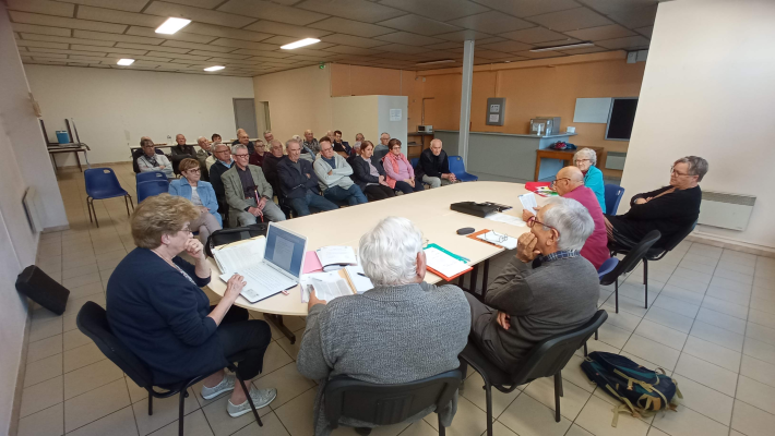 Réunion autour d'une table avec ordinateur portable, documents et chaises.