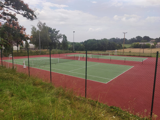 Terrains de tennis avec filet, clôture et éclairage.