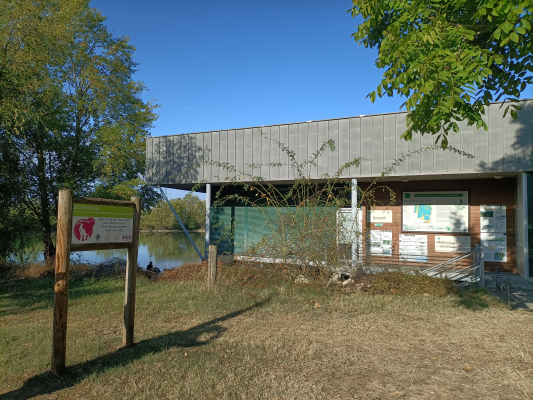 Bâtiment avec panneau, cheminée, porte, fenêtre et vue sur l'eau.