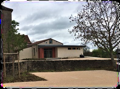 Maison blanche avec toiture grise, arbres et clôture visible.