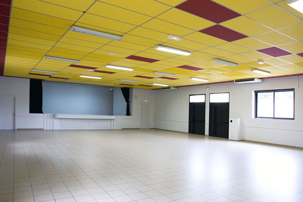 Salle vide avec plafond jaune, murs blancs, portes noires, fenêtres et comptoir.