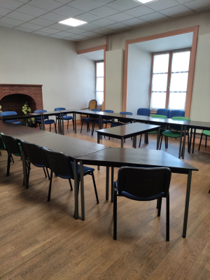 Salle de classe avec tables, chaises, tableau blanc et armoire.