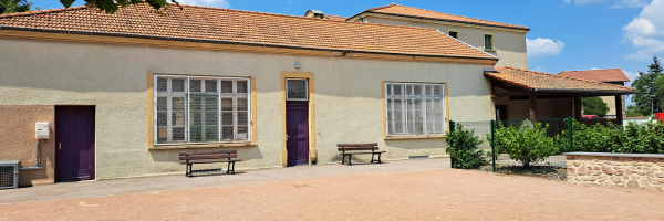 Bâtiment avec fenêtres, portes, bancs et végétation.