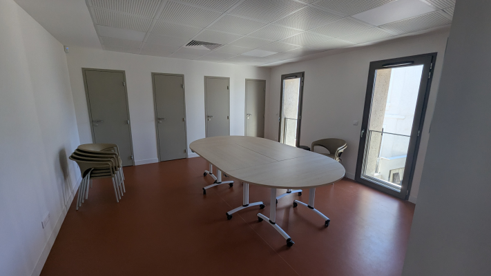 Salle avec table ovale, chaises, portes et fenêtre.