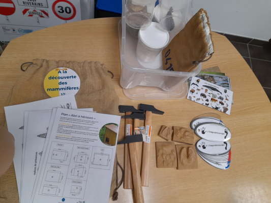 Table avec outils, cartes, documents, sac en toile et boîte en plastique.