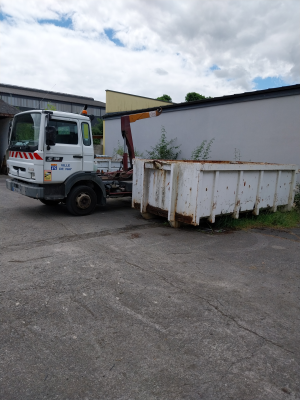 Camion avec grue et benne sur parking.