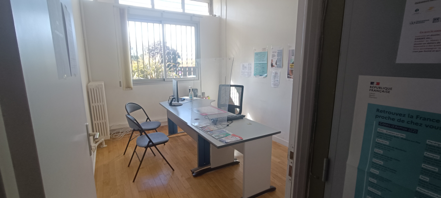 Bureau avec chaise, ordinateur, imprimante, radiateur et affiches murales.