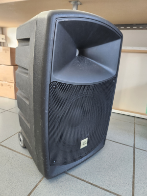 Haut-parleur noir avec roues sur sol carrelé.