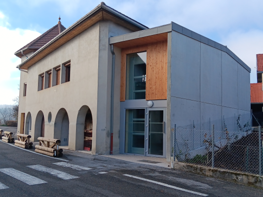 Bâtiment avec façade mixte, arches, grandes fenêtres et porte vitrée.