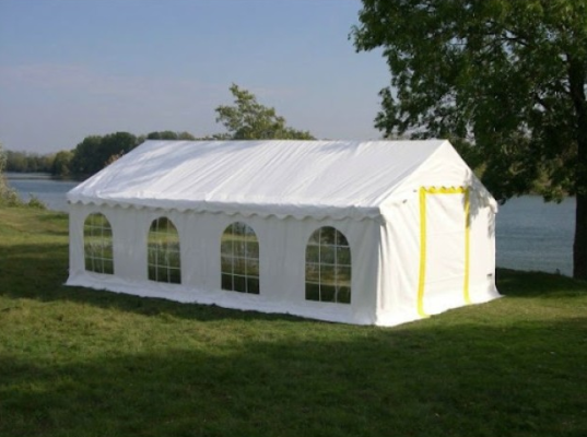 Tente blanche avec fenêtres sur un terrain herbeux près d'un plan d'eau.