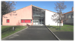 Bâtiment avec entrée, allée, arbres, et store.