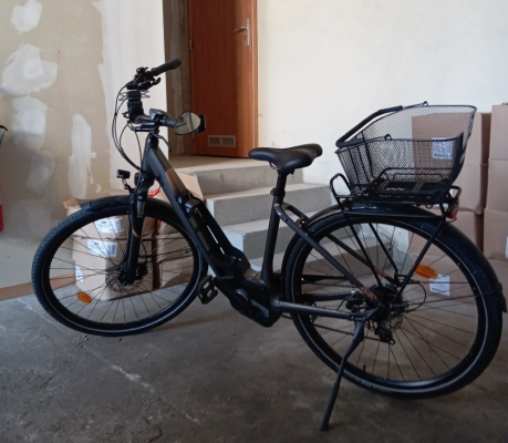 Vélo noir avec panier et brique près d'une porte.