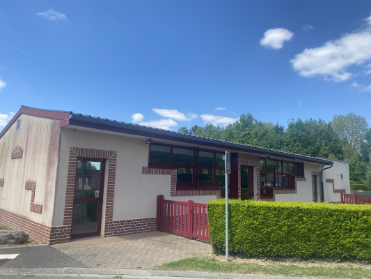 Bâtiment avec porte, fenêtres et clôture.