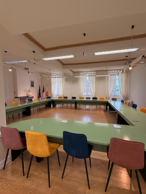 Salle de réunion avec table, chaises, projecteur et écran.
