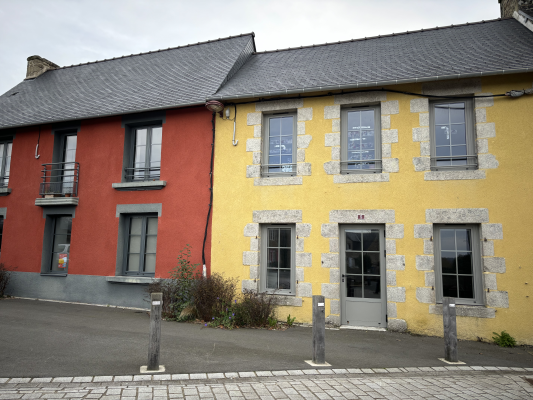 Maison mitoyenne, deux couleurs (rouge et jaune), toit en ardoise, fenêtres avec volets, porte d'entrée.