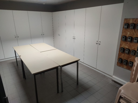 Salle avec table, chaises, armoires et tableau électrique.