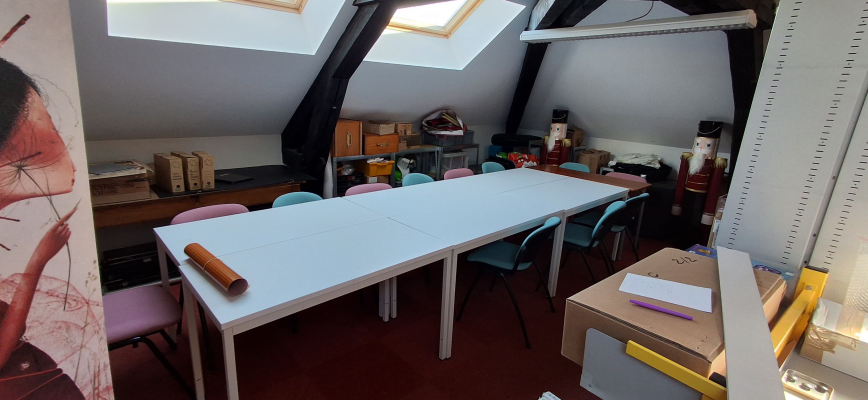 Salle avec table, chaises, étagères, bureau, matériel de construction et fenêtres.