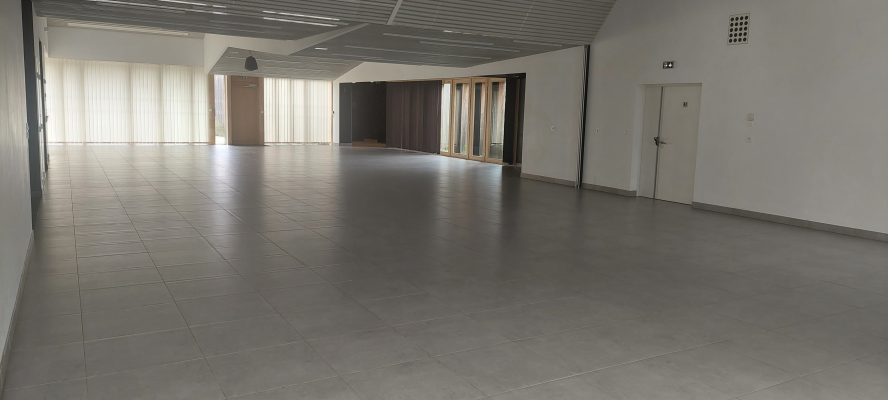 Salle vide avec sol carrelé, portes et fenêtres.