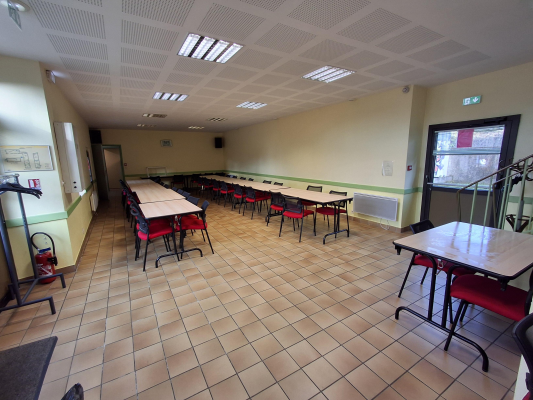 Salle avec tables, chaises, escalator et porte.
