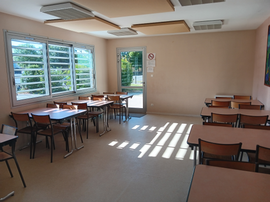 Salle de classe avec tables, chaises, fenêtres et porte.