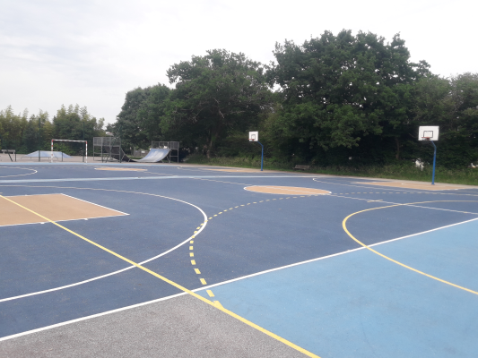 Terrain de basket avec paniers, lignes de jeu et toboggan.