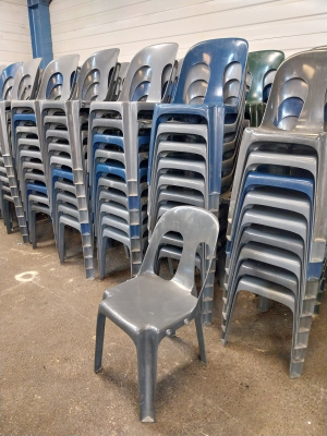 Piles de chaises en plastique empilées dans un entrepôt.